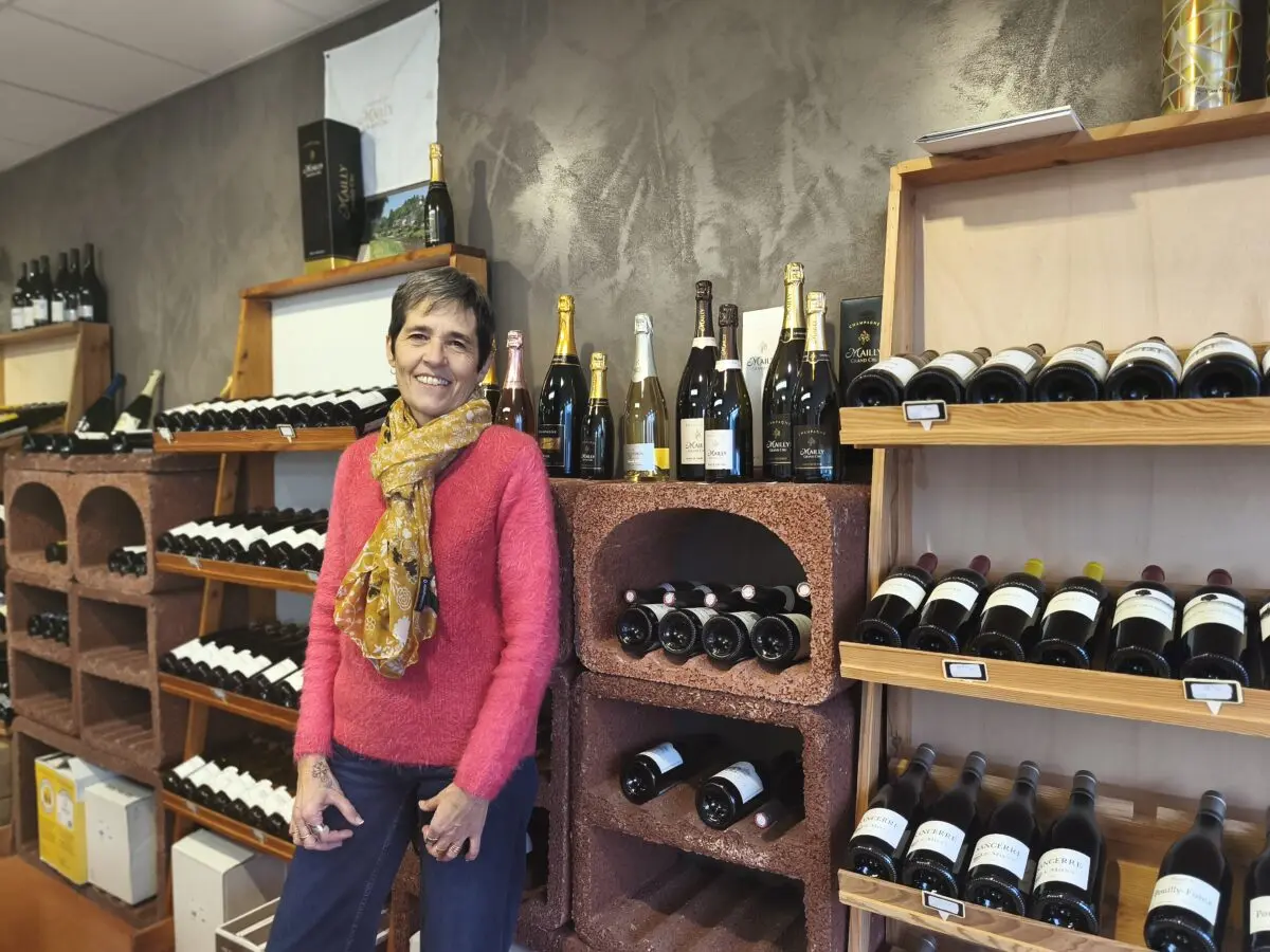Sophie dans la boutique, devant les rayonnages de vins et de champagnes.